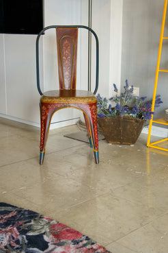 Vista frontale della sedia vintage in ferro con decorazioni floreali dipinte a mano