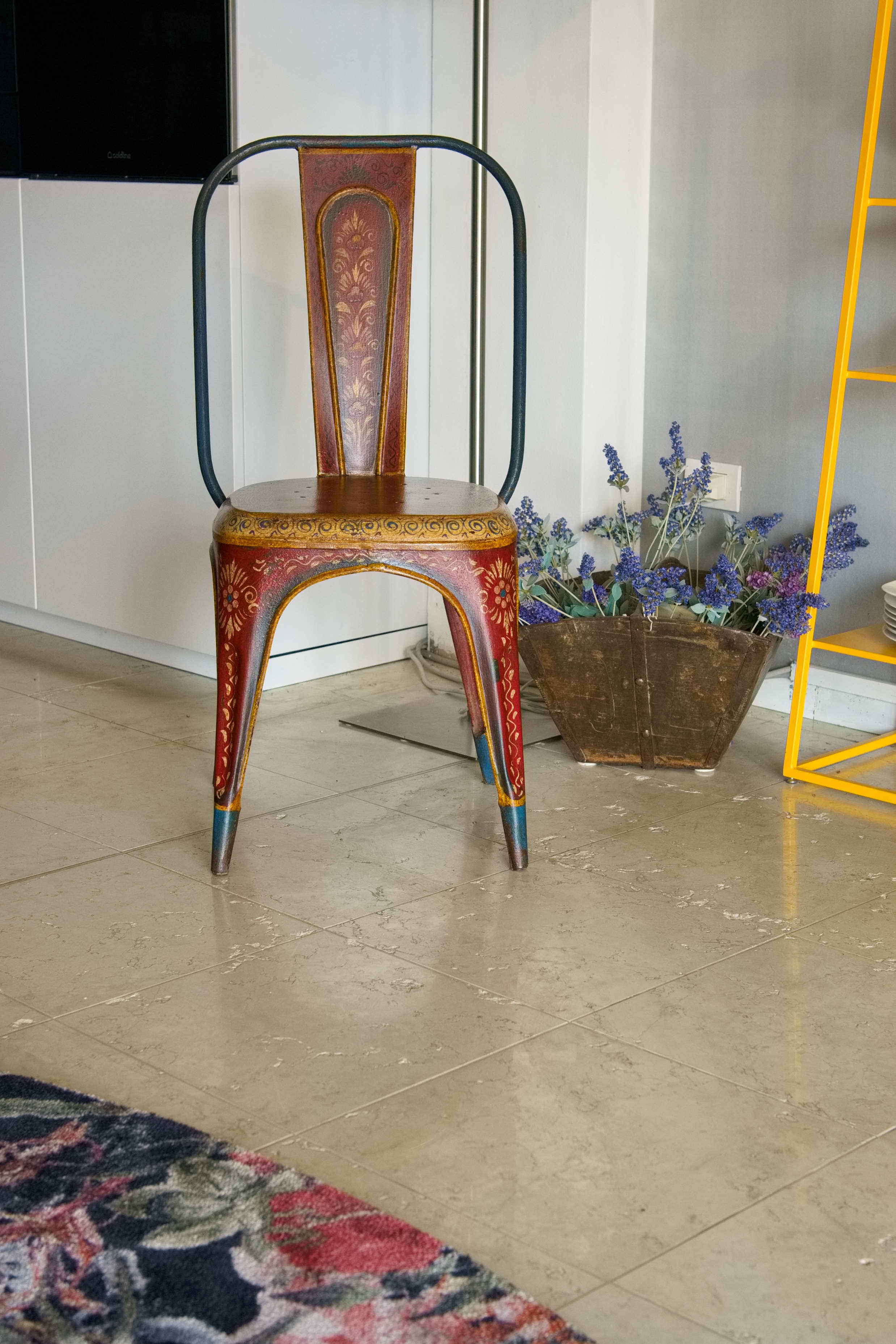 Vista frontale della sedia vintage in ferro con decorazioni floreali dipinte a mano