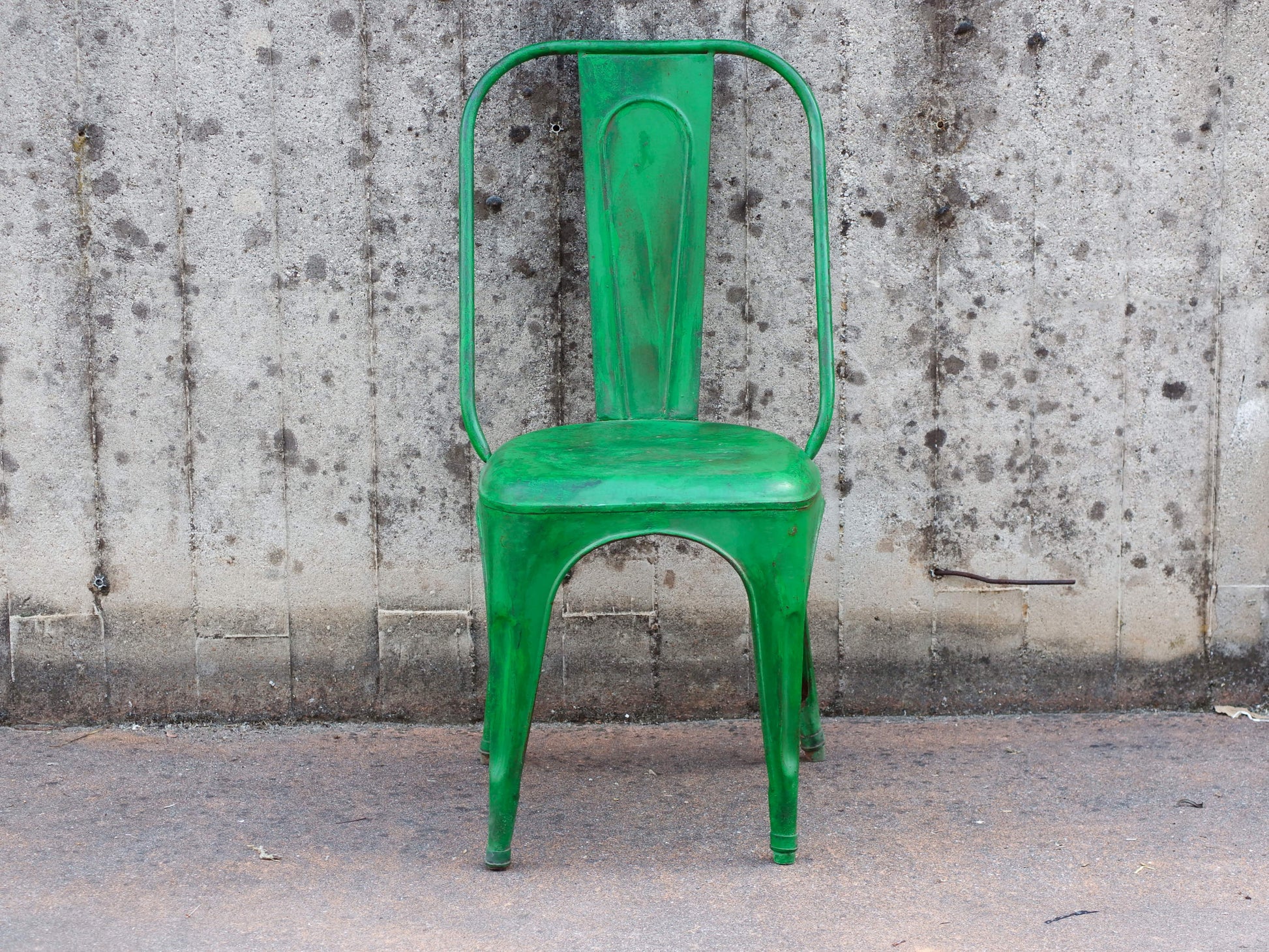Vista frontale della sedia vintage in ferro con finitura verde brillante e patina anticata.