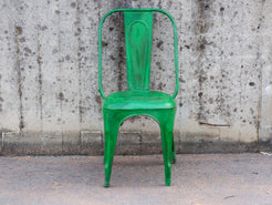 Vista frontale della sedia vintage in ferro con finitura verde brillante e patina anticata.