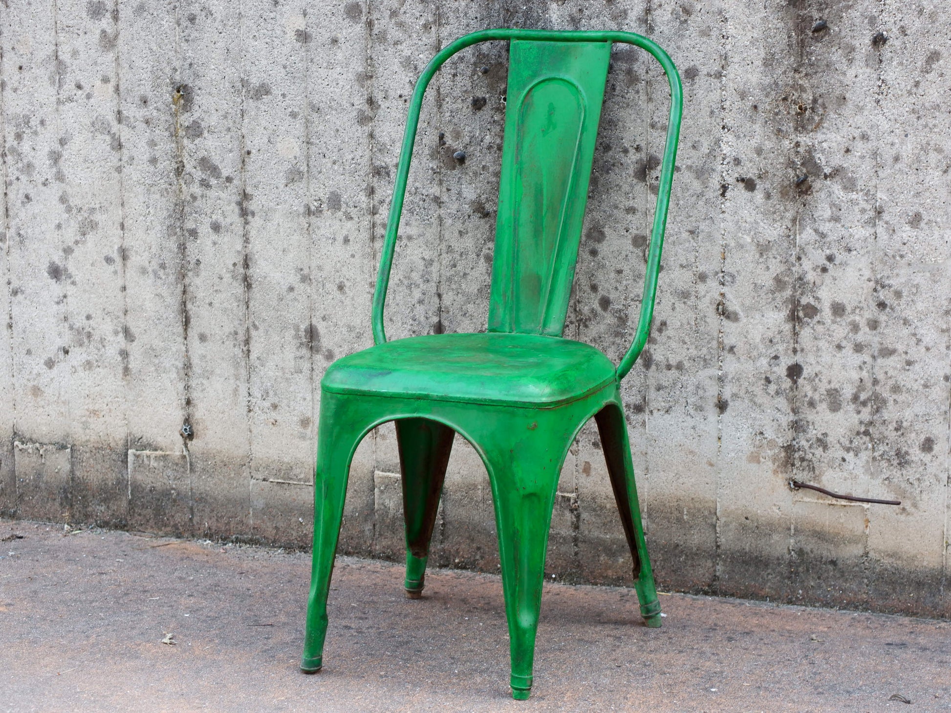 Vista frontale della sedia vintage in ferro con finitura verde brillante e patina anticata.