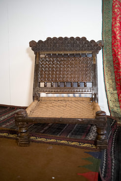 Vista frontale dello sgabello indiano antico Pida in teak con intagli floreali.