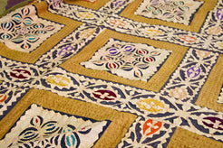Dettaglio ravvicinato dei ricami floreali multicolore all'interno dei riquadri centrali.