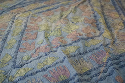Dettaglio ravvicinato dei ricami artigianali colorati sulla superficie in cotone.