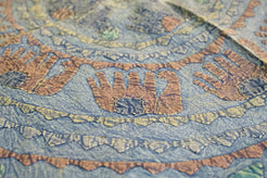 Dettaglio ravvicinato dei ricami artigianali colorati sulla superficie in cotone.