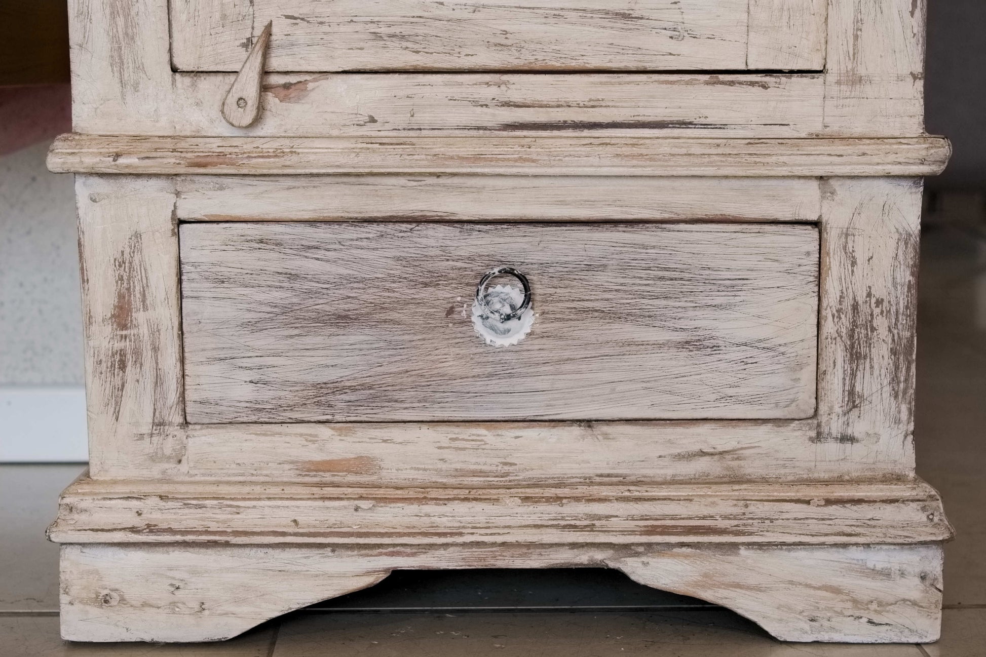 Primo piano del cassetto inferiore e delle finiture decapate su mobile dispensa in legno di teak.