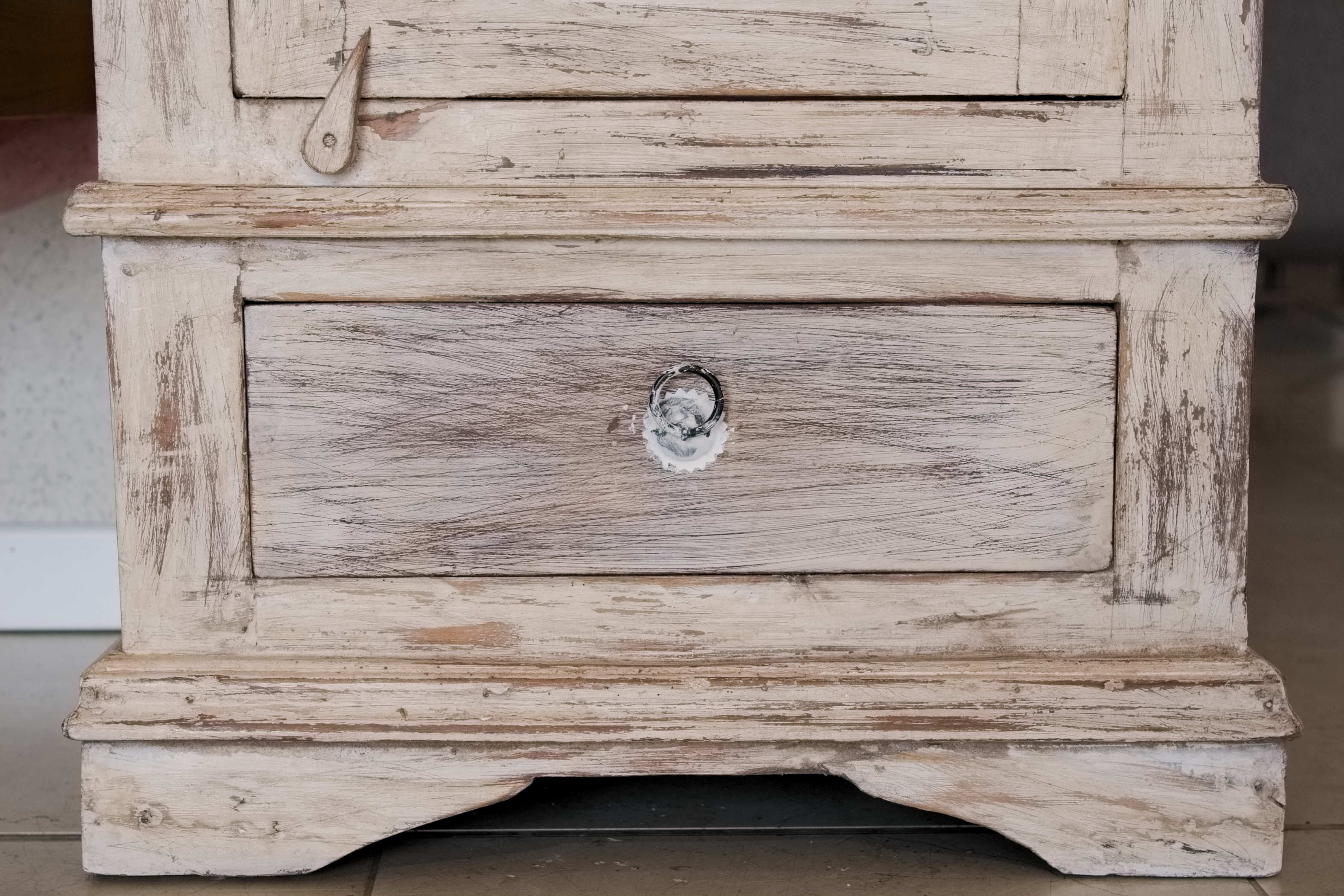 Primo piano del cassetto inferiore e delle finiture decapate su mobile dispensa in legno di teak.