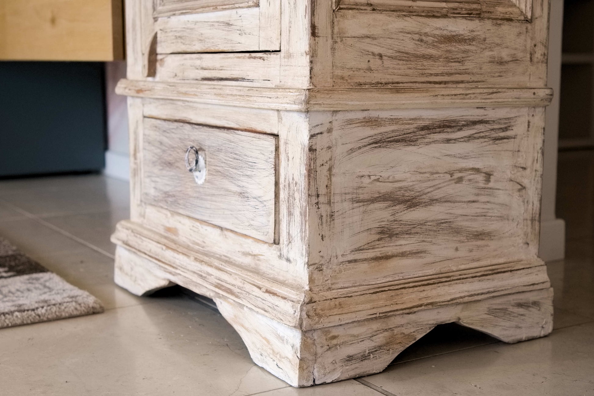 Primo piano del cassetto inferiore e delle finiture decapate su mobile dispensa in legno di teak.