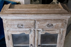 Primo piano delle ante inferiori con vetri trasparenti e cornici sagomate su armadietto in stile vintage.