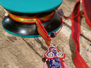 DAMARU TIBETANO originale nepalese , costruito a mano . dipinto e ricamato secondo lo stile e i simboli tibetani buddisti .  Membranofono a percussione. Strumento musicale e rituale composto da una doppia cassa, ricoperta di cuoio, che viene percosso con due piccole sfere legate a delle cordicelle. La rotazione permette di suonarlo E' lo strumento sacro prediletto dal dio Shiva  diam 23 h10 cm 