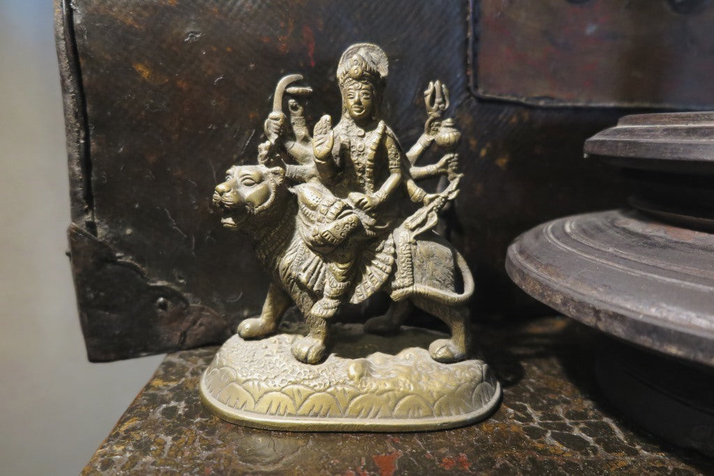 statuetta di Durga indiana in metallo inciso artigianalmente .   Presso la religione induista  "colei che difficilmente si può avvicinare" è una forma di Devi , ovvero della Madre Divina (che assume anche molte altre forme, tra cui Sarasvati , Parvati, Lakshmi, Kālī). È raffigurata come una donna che cavalca un leone, sebbene più raramente la si trovi raffigurata anche su una tigre, con numerose braccia mani che impugnano diversi tipi di armi e fanno dei mudrā (gesti simbolici fatti con la mano). Questa for