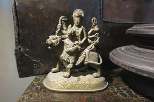 statuetta di Durga indiana in metallo inciso artigianalmente .   Presso la religione induista  "colei che difficilmente si può avvicinare" è una forma di Devi , ovvero della Madre Divina (che assume anche molte altre forme, tra cui Sarasvati , Parvati, Lakshmi, Kālī). È raffigurata come una donna che cavalca un leone, sebbene più raramente la si trovi raffigurata anche su una tigre, con numerose braccia mani che impugnano diversi tipi di armi e fanno dei mudrā (gesti simbolici fatti con la mano). Questa for