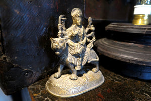 statuetta di Durga indiana in metallo inciso artigianalmente .   Presso la religione induista  "colei che difficilmente si può avvicinare" è una forma di Devi , ovvero della Madre Divina (che assume anche molte altre forme, tra cui Sarasvati , Parvati, Lakshmi, Kālī). È raffigurata come una donna che cavalca un leone, sebbene più raramente la si trovi raffigurata anche su una tigre, con numerose braccia mani che impugnano diversi tipi di armi e fanno dei mudrā (gesti simbolici fatti con la mano). Questa for