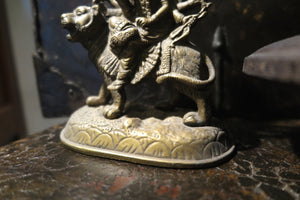 statuetta di Durga indiana in metallo inciso artigianalmente .   Presso la religione induista  "colei che difficilmente si può avvicinare" è una forma di Devi , ovvero della Madre Divina (che assume anche molte altre forme, tra cui Sarasvati , Parvati, Lakshmi, Kālī). È raffigurata come una donna che cavalca un leone, sebbene più raramente la si trovi raffigurata anche su una tigre, con numerose braccia mani che impugnano diversi tipi di armi e fanno dei mudrā (gesti simbolici fatti con la mano). Questa for