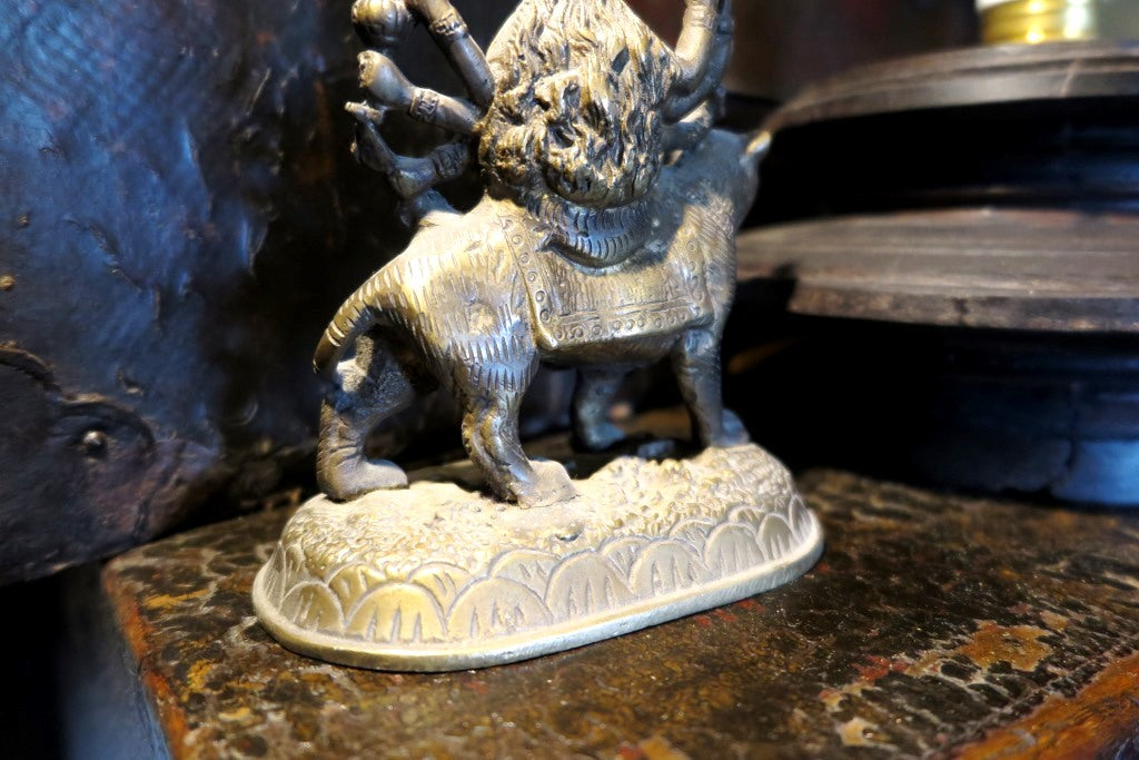 statuetta di Durga indiana in metallo inciso artigianalmente .   Presso la religione induista  "colei che difficilmente si può avvicinare" è una forma di Devi , ovvero della Madre Divina (che assume anche molte altre forme, tra cui Sarasvati , Parvati, Lakshmi, Kālī). È raffigurata come una donna che cavalca un leone, sebbene più raramente la si trovi raffigurata anche su una tigre, con numerose braccia mani che impugnano diversi tipi di armi e fanno dei mudrā (gesti simbolici fatti con la mano). Questa for