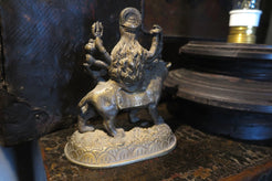 statuetta di Durga indiana in metallo inciso artigianalmente .   Presso la religione induista  "colei che difficilmente si può avvicinare" è una forma di Devi , ovvero della Madre Divina (che assume anche molte altre forme, tra cui Sarasvati , Parvati, Lakshmi, Kālī). È raffigurata come una donna che cavalca un leone, sebbene più raramente la si trovi raffigurata anche su una tigre, con numerose braccia mani che impugnano diversi tipi di armi e fanno dei mudrā (gesti simbolici fatti con la mano). Questa for