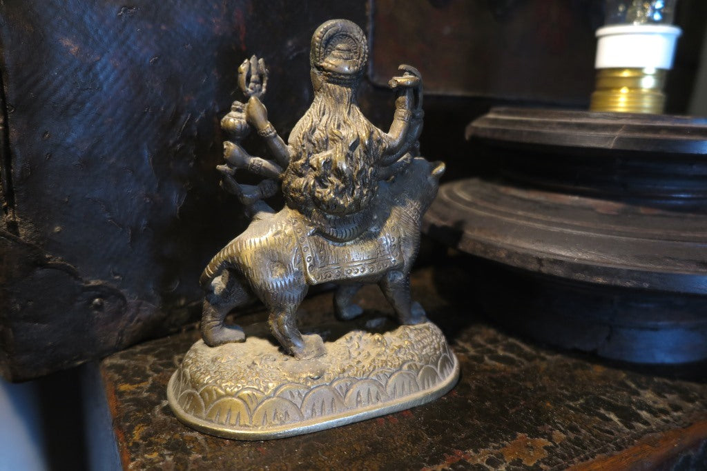 statuetta di Durga indiana in metallo inciso artigianalmente .   Presso la religione induista  "colei che difficilmente si può avvicinare" è una forma di Devi , ovvero della Madre Divina (che assume anche molte altre forme, tra cui Sarasvati , Parvati, Lakshmi, Kālī). È raffigurata come una donna che cavalca un leone, sebbene più raramente la si trovi raffigurata anche su una tigre, con numerose braccia mani che impugnano diversi tipi di armi e fanno dei mudrā (gesti simbolici fatti con la mano). Questa for