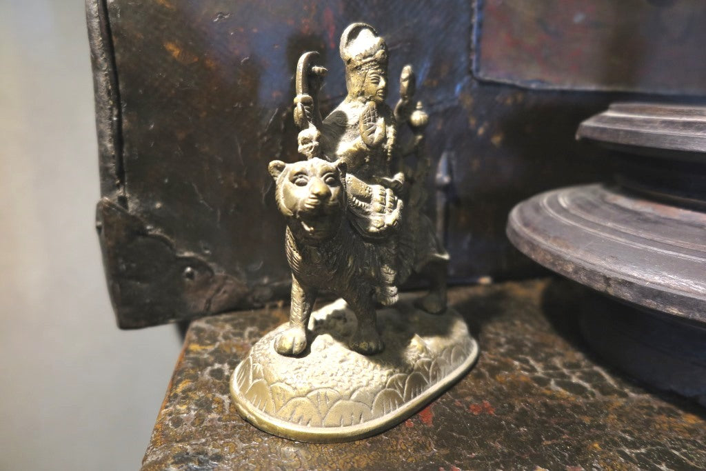 statuetta di Durga indiana in metallo inciso artigianalmente .   Presso la religione induista  "colei che difficilmente si può avvicinare" è una forma di Devi , ovvero della Madre Divina (che assume anche molte altre forme, tra cui Sarasvati , Parvati, Lakshmi, Kālī). È raffigurata come una donna che cavalca un leone, sebbene più raramente la si trovi raffigurata anche su una tigre, con numerose braccia mani che impugnano diversi tipi di armi e fanno dei mudrā (gesti simbolici fatti con la mano). Questa for
