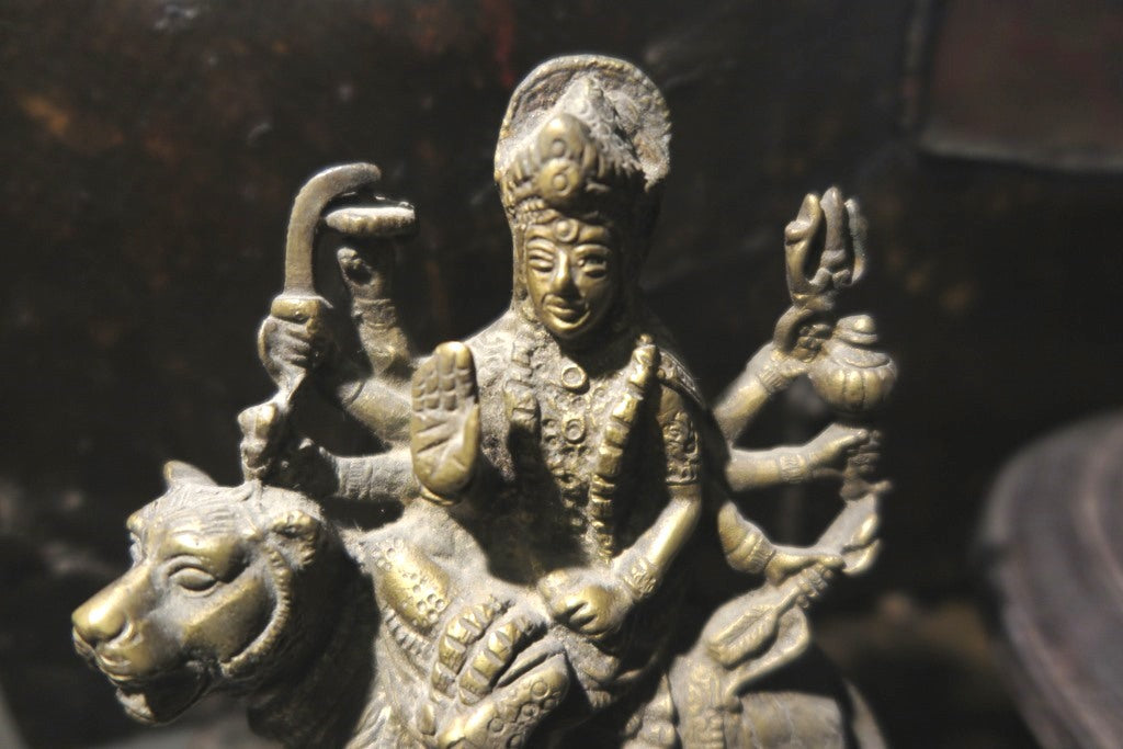 statuetta di Durga indiana in metallo inciso artigianalmente .   Presso la religione induista  "colei che difficilmente si può avvicinare" è una forma di Devi , ovvero della Madre Divina (che assume anche molte altre forme, tra cui Sarasvati , Parvati, Lakshmi, Kālī). È raffigurata come una donna che cavalca un leone, sebbene più raramente la si trovi raffigurata anche su una tigre, con numerose braccia mani che impugnano diversi tipi di armi e fanno dei mudrā (gesti simbolici fatti con la mano). Questa for