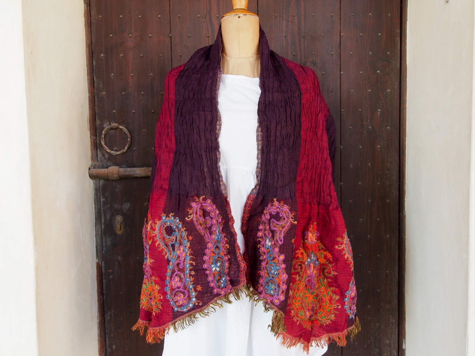 scialle in lana ricamato . lana elasticizzata , ricamo a mano a tema floreale .  double faces : - un lato bordeaux e nero  -un lato verde / marrone  finito a "V" alle estremità  pezzo unico lavorato aetigianalmente  proveniente dall'india in lana pettinata molto calda e poco pesante .  misure : 60 x 200cm