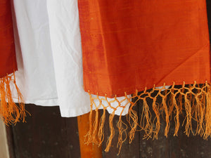 Scialle indiano in shantung di seta , un tessuto di seta selvaggia, di colore unito, caratterizzato da una superficie ruvida, molto irregolare e dall'aspetto grezzo di colore arancione.