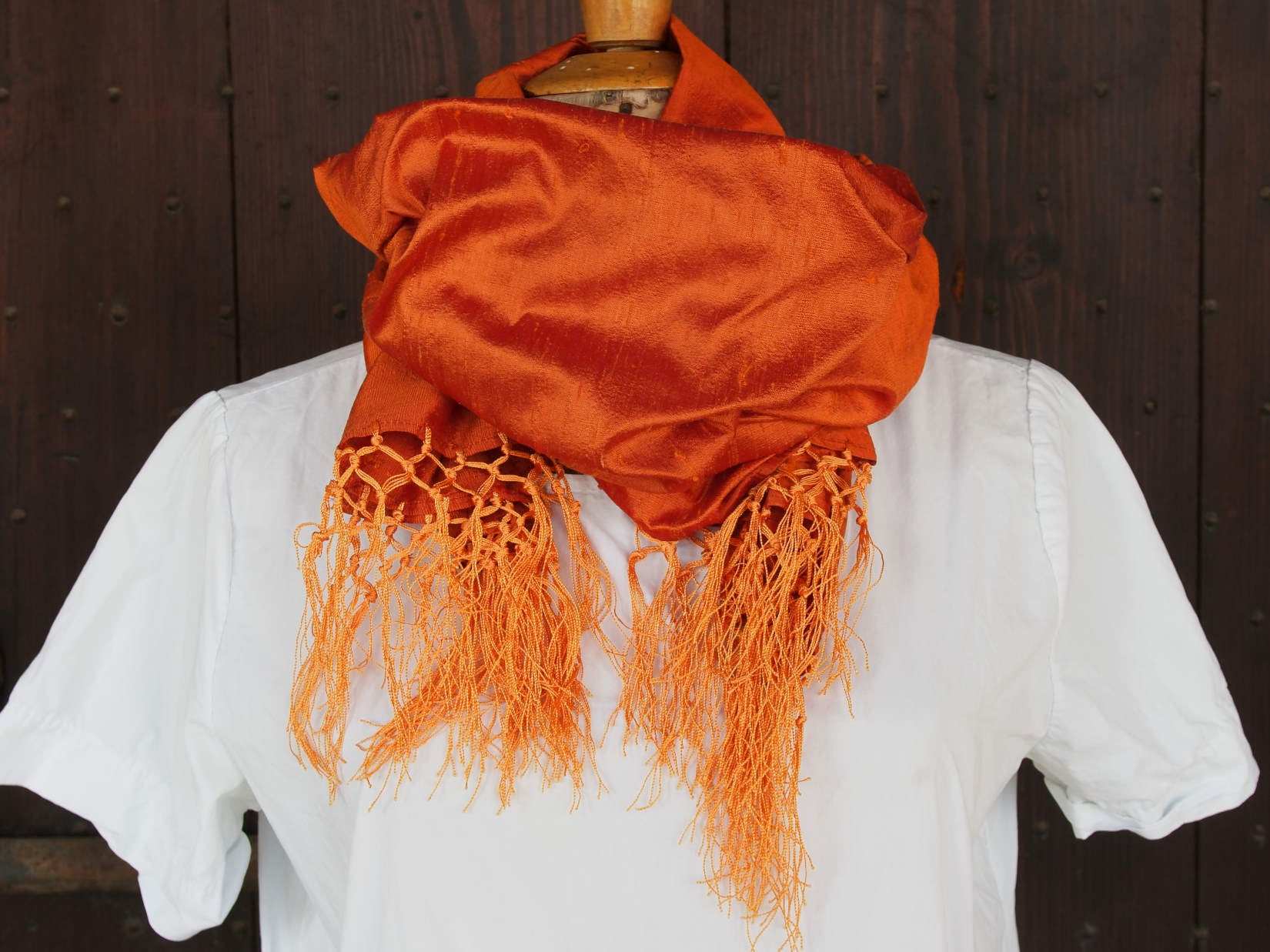 Scialle indiano in shantung di seta , un tessuto di seta selvaggia, di colore unito, caratterizzato da una superficie ruvida, molto irregolare e dall'aspetto grezzo di colore arancione.