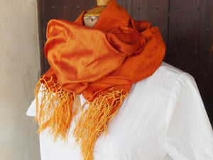 Scialle indiano in shantung di seta , un tessuto di seta selvaggia, di colore unito, caratterizzato da una superficie ruvida, molto irregolare e dall'aspetto grezzo di colore arancione.