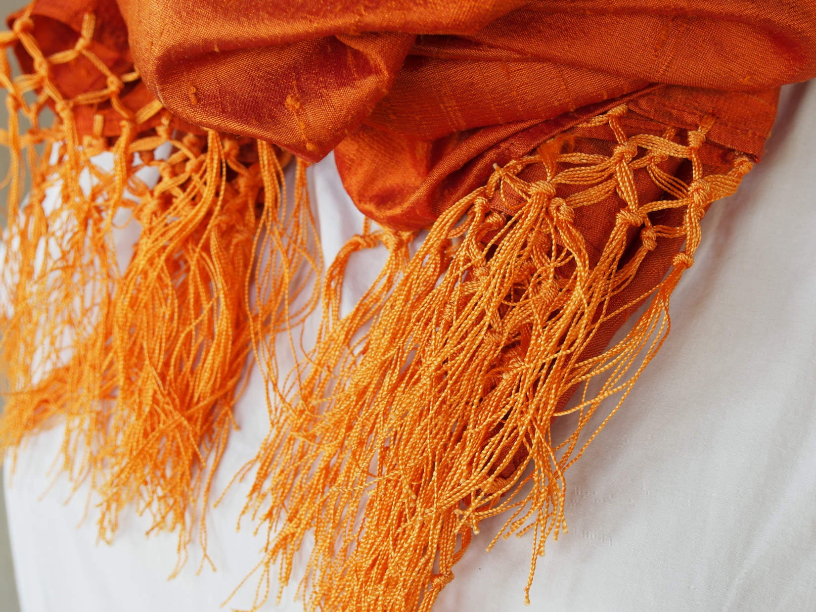 Scialle indiano in shantung di seta , un tessuto di seta selvaggia, di colore unito, caratterizzato da una superficie ruvida, molto irregolare e dall'aspetto grezzo di colore arancione.