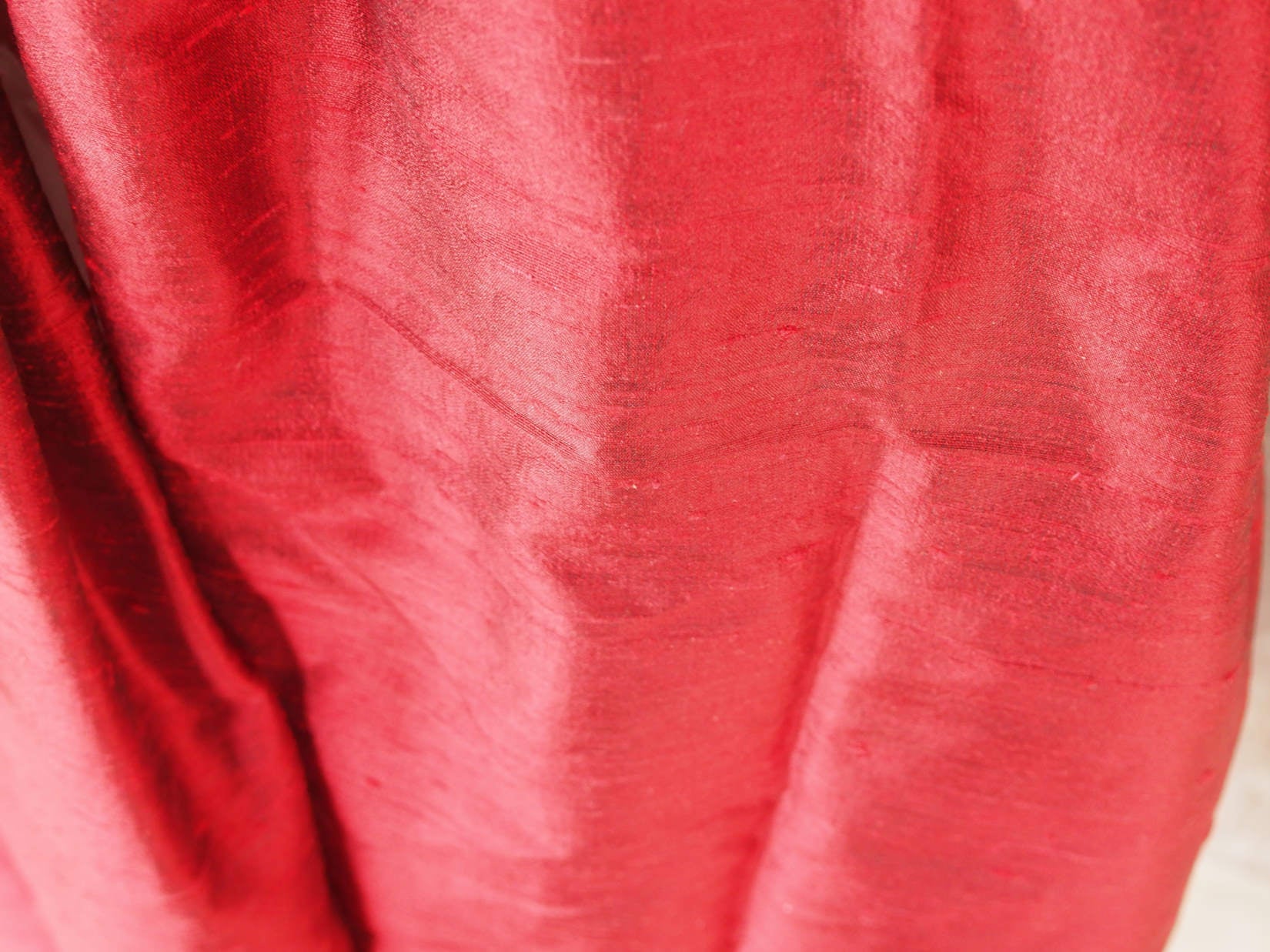 Scialle indiano in shantung di seta , un tessuto di seta selvaggia, di colore unito, caratterizzato da una superficie ruvida, molto irregolare e dall'aspetto grezzo di colore rosso.