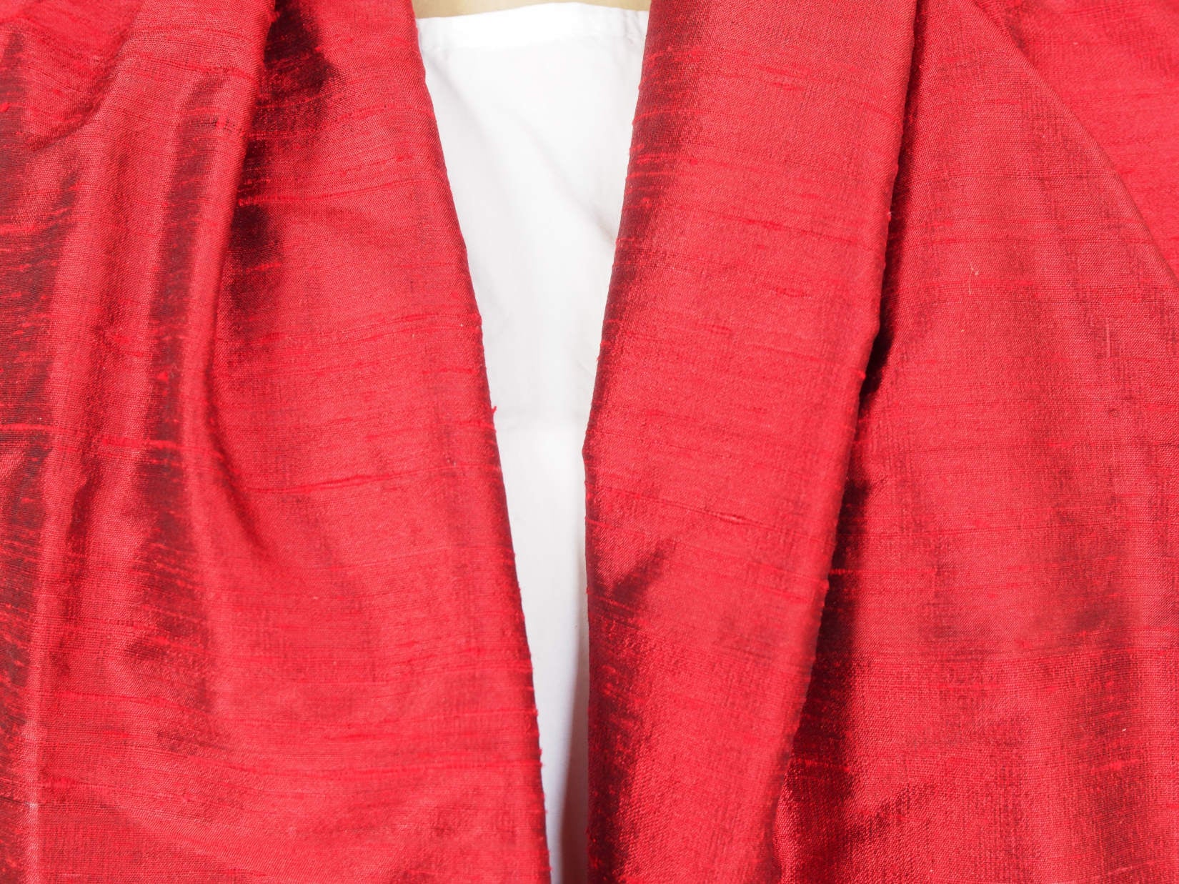 Scialle indiano in shantung di seta , un tessuto di seta selvaggia, di colore unito, caratterizzato da una superficie ruvida, molto irregolare e dall'aspetto grezzo di colore rosso.