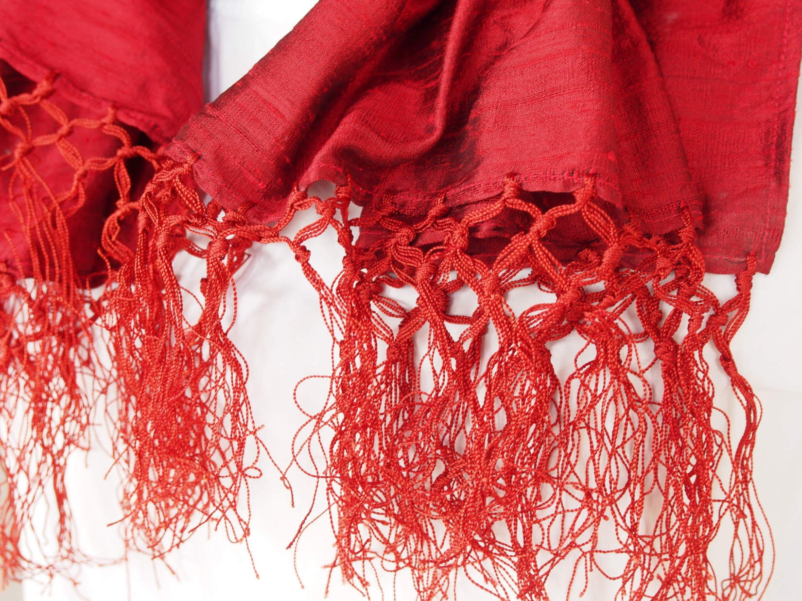 Scialle indiano in shantung di seta , un tessuto di seta selvaggia, di colore unito, caratterizzato da una superficie ruvida, molto irregolare e dall'aspetto grezzo di colore rosso.