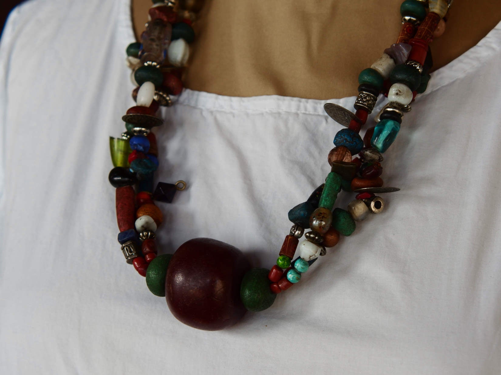 Collana tribale Amazigh, Berbera. Fatta a mano da artigiani berberi tradizionali con perline in ceramica, cristalli, pelle, pietre, corna, resine vegetali naturali e alcune piccole monete vecchie. La pietra centrale di un colore giallo intenso è di diametro 4cm circa, è leggermente ovalizzata. Pezzo unico di origine tribale , disponibili altri modelli oltre a quelli fotografati.  lunghezza 70cm, peso 170 gr