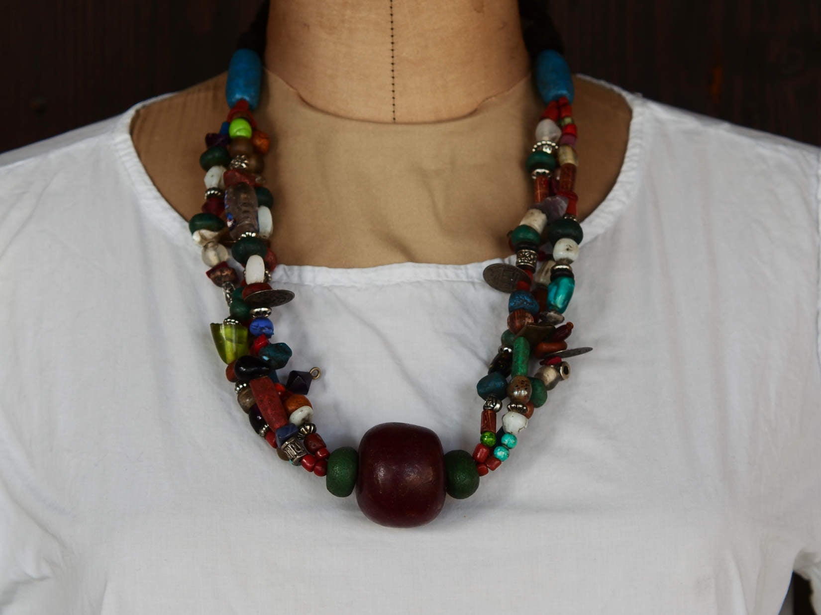 Collana tribale Amazigh, Berbera. Fatta a mano da artigiani berberi tradizionali con perline in ceramica, cristalli, pelle, pietre, corna, resine vegetali naturali e alcune piccole monete vecchie. La pietra centrale di un colore giallo intenso è di diametro 4cm circa, è leggermente ovalizzata. Pezzo unico di origine tribale , disponibili altri modelli oltre a quelli fotografati.  lunghezza 70cm, peso 170 gr
