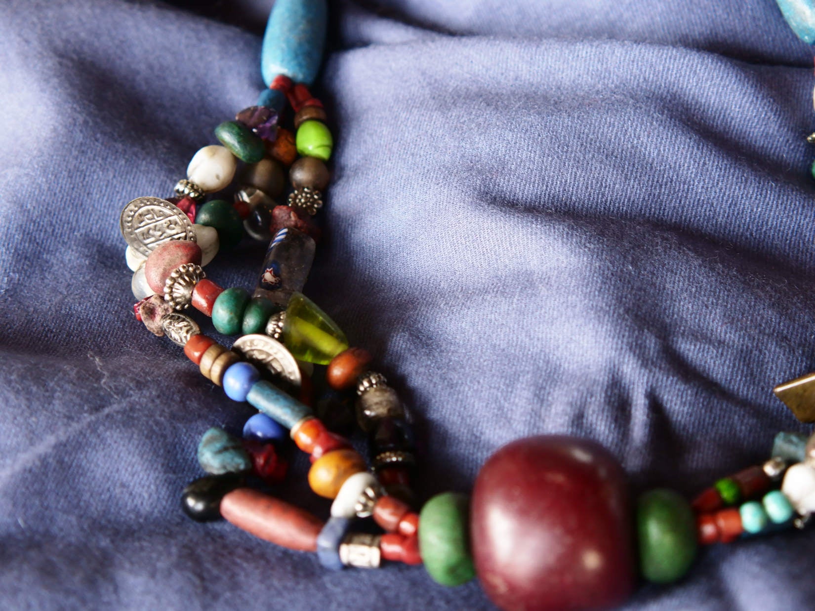 Collana tribale Amazigh, Berbera. Fatta a mano da artigiani berberi tradizionali con perline in ceramica, cristalli, pelle, pietre, corna, resine vegetali naturali e alcune piccole monete vecchie. La pietra centrale di un colore giallo intenso è di diametro 4cm circa, è leggermente ovalizzata. Pezzo unico di origine tribale , disponibili altri modelli oltre a quelli fotografati.  lunghezza 70cm, peso 170 gr