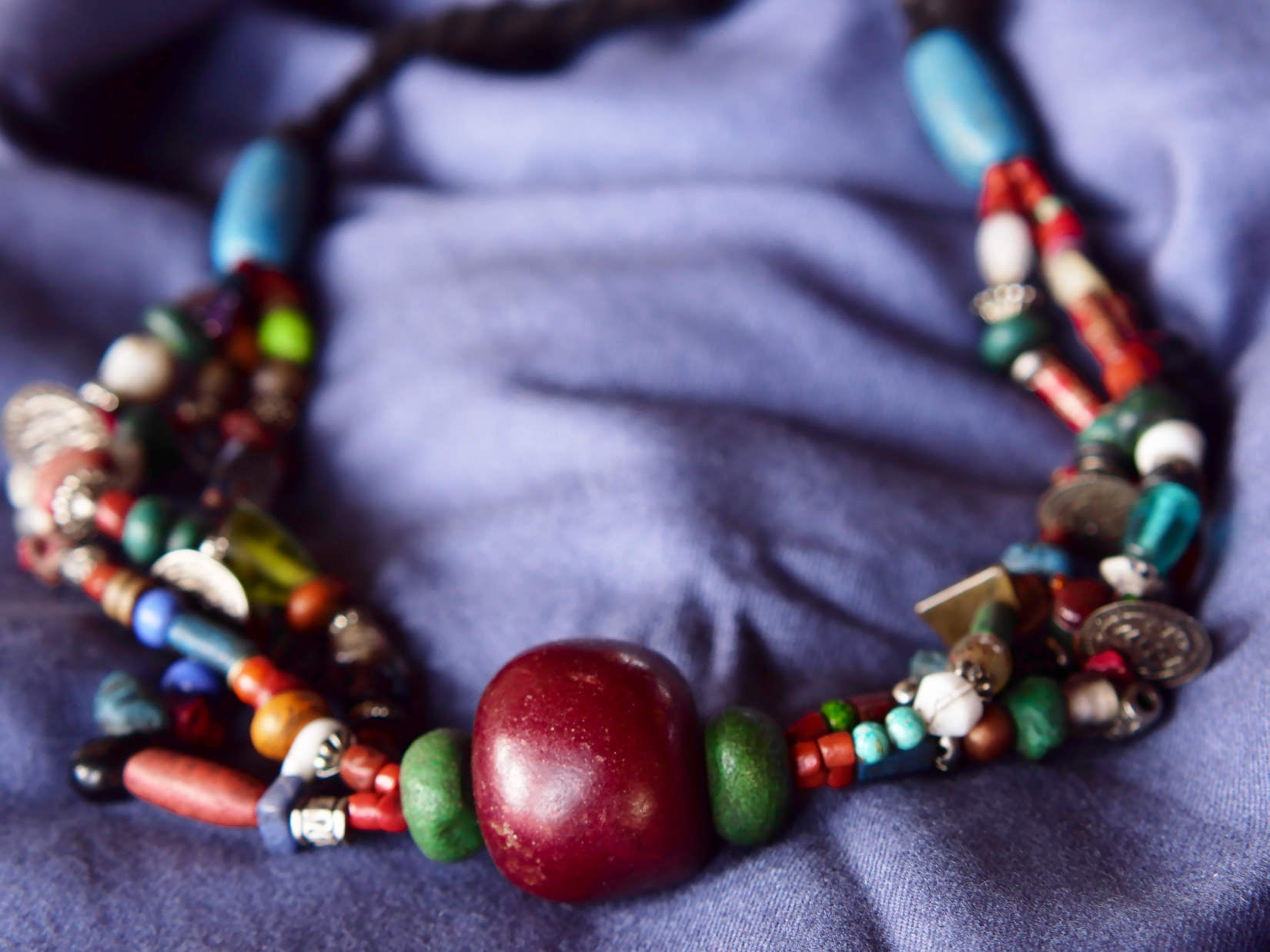 Collana tribale Amazigh, Berbera. Fatta a mano da artigiani berberi tradizionali con perline in ceramica, cristalli, pelle, pietre, corna, resine vegetali naturali e alcune piccole monete vecchie. La pietra centrale di un colore giallo intenso è di diametro 4cm circa, è leggermente ovalizzata. Pezzo unico di origine tribale , disponibili altri modelli oltre a quelli fotografati.  lunghezza 70cm, peso 170 gr