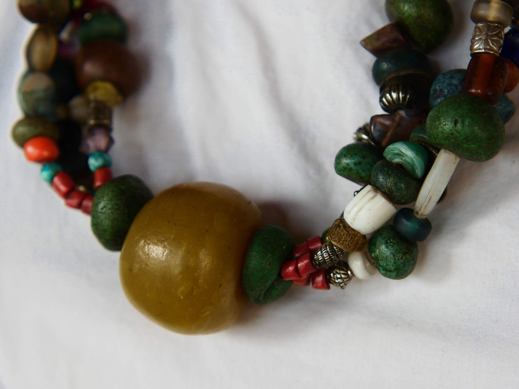 Collana tribale Amazigh, Berbera. Fatta a mano da artigiani berberi tradizionali con perline in ceramica, cristalli, pelle, pietre, corna, resine vegetali naturali e alcune piccole monete vecchie. La pietra centrale di un colore giallo intenso è di diametro 4cm circa, è leggermente ovalizzata. Pezzo unico di origine tribale , disponibili altri modelli oltre a quelli fotografati.  lunghezza 80cm, peso 230 gr