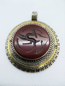 vecchio pendaglio afgano in argento cesellato e corniola incisa .  pezzo unico databile seconda metà 900 , originale in ogni parte e lavorato artigianalmente.  incisioni spesso con frasi tratte dal corano o , essendo un oggetto che viene tramandato da generazione in generazione , frasi di buon auspicio ( Come un Hamsa o l'Occhio blu si suppone di proteggere contro il male e garantire il successo per il portatore del ciondolo  )  spedizione italia  compresa     peso 41 gr  dimensioni 4,5 x 4,5   
