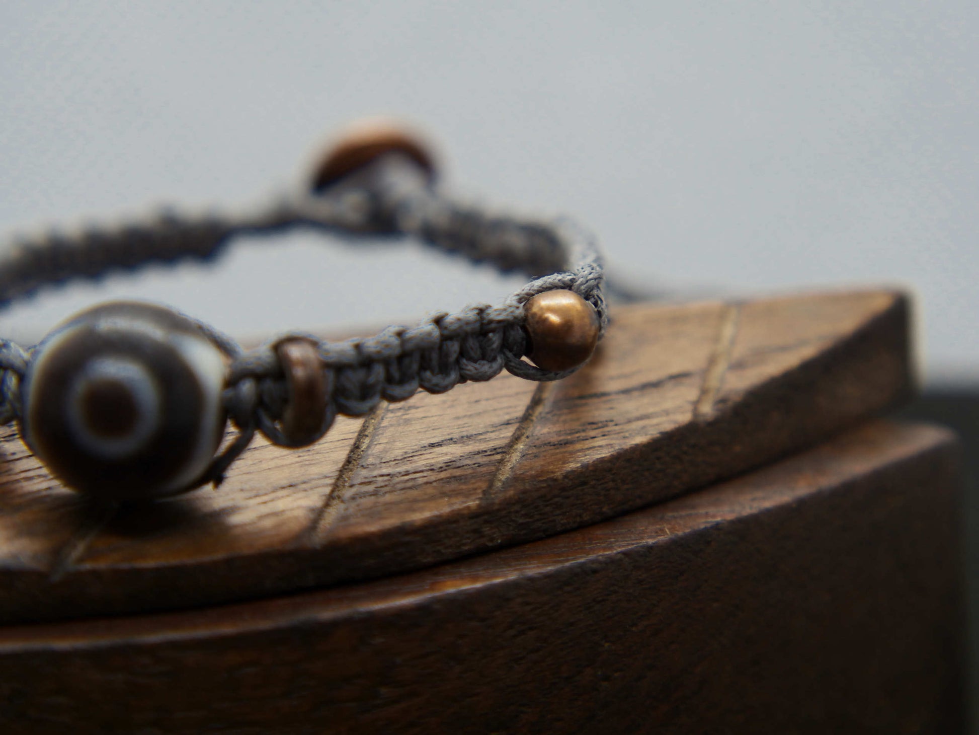 bracciale intrecciato con dzi in agata , chiusura a bottone regolabile in misura.