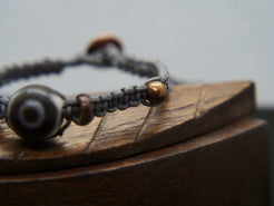 bracciale intrecciato con dzi in agata , chiusura a bottone regolabile in misura.