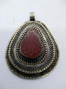 vecchio pendaglio afgano in argento cesellato e corniola incisa .  pezzo unico databile seconda metà 900 , originale in ogni parte e lavorato artigianalmente.  incisioni spesso con frasi tratte dal corano o , essendo un oggetto che viene tramandato da generazione in generazione , frasi di buon auspicio ( Come un Hamsa o l'Occhio blu si suppone di proteggere contro il male e garantire il successo per il portatore del ciondolo  )  spedizione italia  compresa   peso 37 gr  dimensioni 6x4,5 cm 