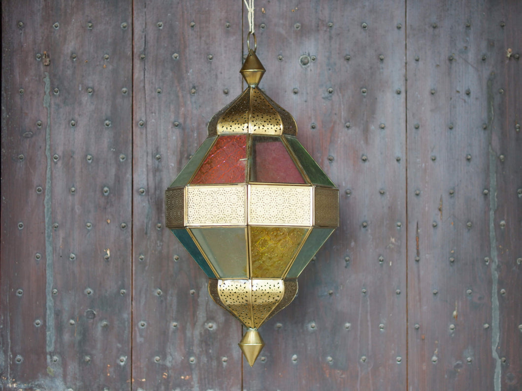 Lanterna indiana in metallo lavorata artigianalmente, finemente decorata a traforo, con vetro multicolor e trasparente.  Disponibile anche nella versione con solo vetro trasparente. Con piccolo portacandele interno e gancio per appendere .    dimensioni diametro 25  h55  per info ed ulteriori foto info@etniko.it facebook / instagram / pinterest : etnikobycrosato 0039 3338778241