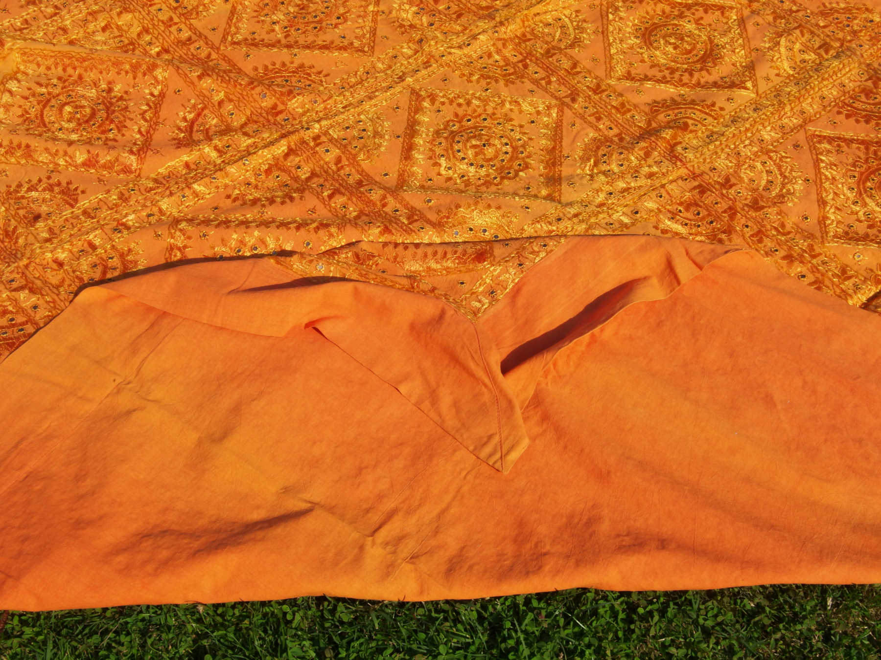 Telo Indiano in cotone doppio strato, ricamato tono su tono con specchietti,  di color arancione. Può essere impiegato come copridivano, copriletto, tovaglia o tessuto da appendere a parete. Dimensioni 215x270cm