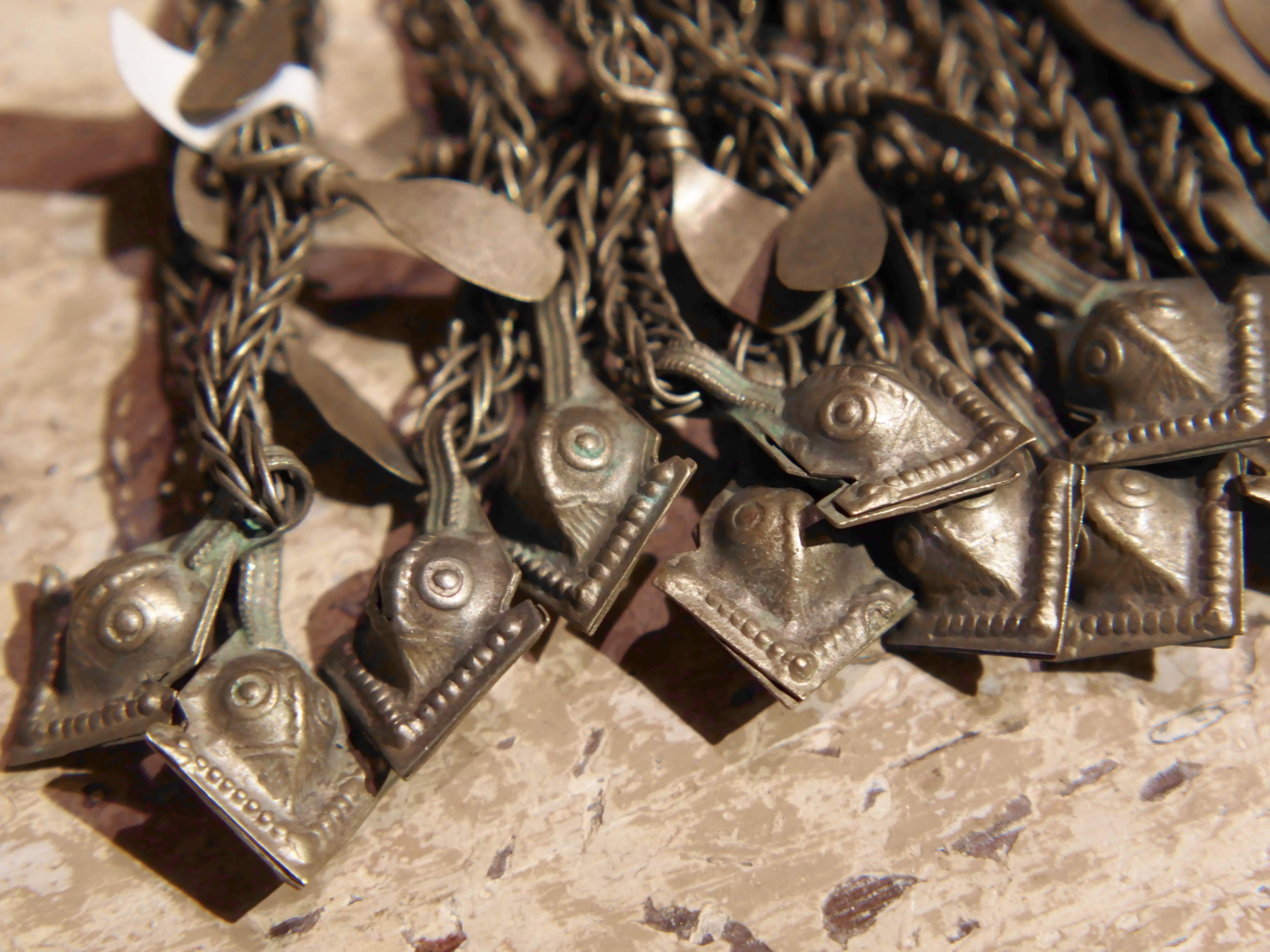 La sezione superiore ha applicate sette ganci decorativi con finale rotondo .  La scatola si apre ad un'estremità e ha un cilindro di rame argento per l'inserimento di oggetti protettivi magici e "mantra".( questo taviz è stato sigillato in modo da non perdere parte dell'oggetto )