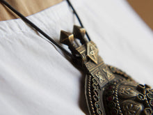 Carica l&#39;immagine nel visualizzatore di Gallery, Questa lunga e massiccia collana proviene probabilmente da una delle tribù nomadi dell&#39;Afghanistan o del Turkmenistan. Il ciondolo ha inscritto motivi floreali e boteh (paisley). Costruito in lega di argento, pezzo unico databile primi 900, conservato perfettamente, le catene che all&#39;estremità hanno una sfera campanellino sono originali e incastrate a mano. Pezzo di difficile reperibilità.  lunghezza totale 20 cm, diametro parte superiore 10 cm, peso 170 gr