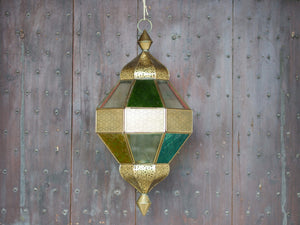Lanterna indiana in metallo lavorata artigianalmente, finemente decorata a traforo, con vetro multicolor e trasparente.  Disponibile anche nella versione con solo vetro trasparente. Con piccolo portacandele interno e gancio per appendere .    dimensioni diametro 25  h55  per info ed ulteriori foto info@etniko.it facebook / instagram / pinterest : etnikobycrosato 0039 3338778241