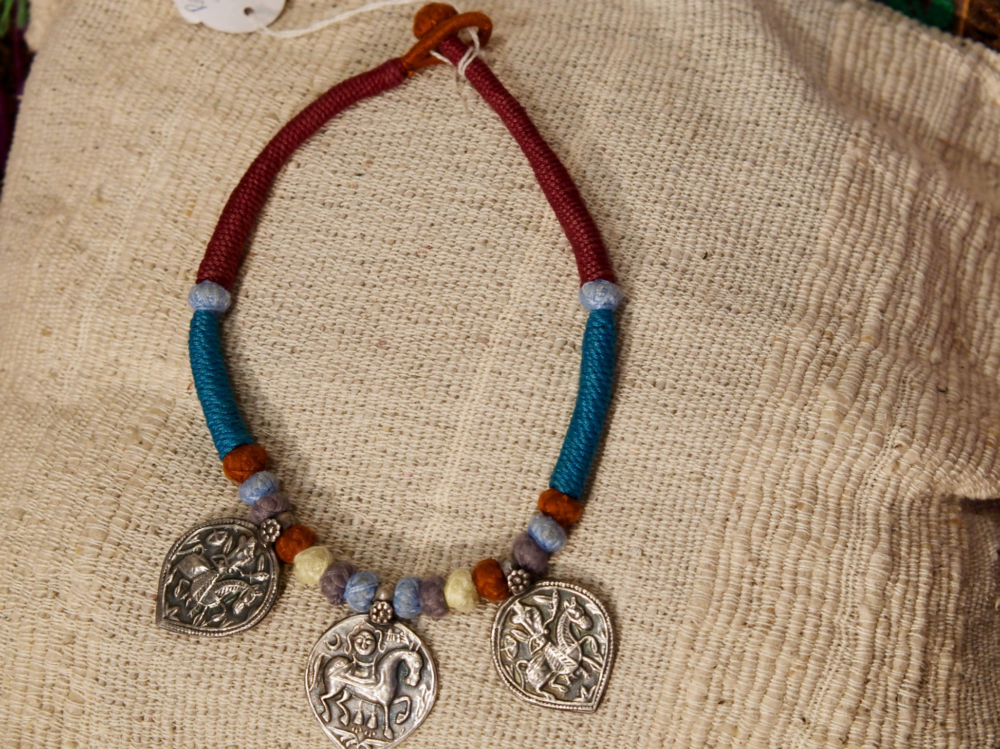 collana in cotone intrecciato con vecchi  pendaglii  raffigurantetipiche figure tribali dell'india del nord .  misure collana 44cm  pendaglio 4.5 x 3  cm  peso 51gr