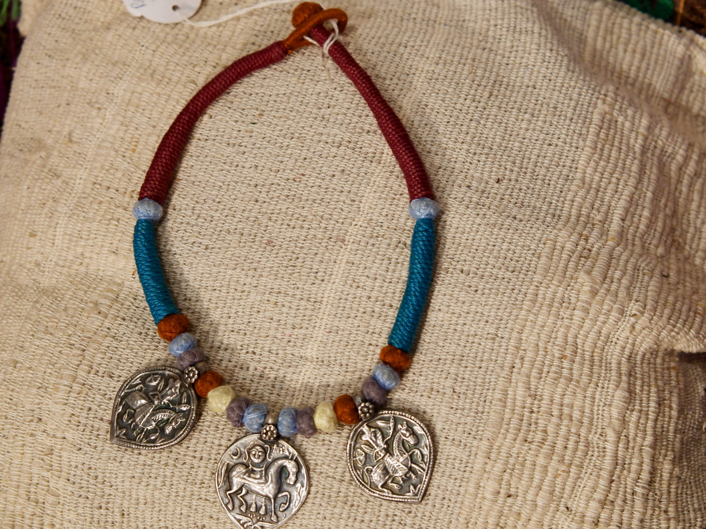 collana in cotone intrecciato con vecchi  pendaglii  raffigurantetipiche figure tribali dell'india del nord .  misure collana 44cm  pendaglio 4.5 x 3  cm  peso 51gr