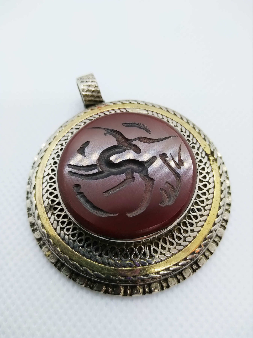 vecchio pendaglio afgano in argento cesellato e corniola incisa .  pezzo unico databile seconda metà 900 , originale in ogni parte e lavorato artigianalmente.  incisioni spesso con frasi tratte dal corano o , essendo un oggetto che viene tramandato da generazione in generazione , frasi di buon auspicio ( Come un Hamsa o l'Occhio blu si suppone di proteggere contro il male e garantire il successo per il portatore del ciondolo  )  spedizione italia  compresa     peso 41 gr  dimensioni 4,5 x 4,5   