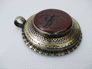 vecchio pendaglio afgano in argento cesellato e corniola incisa .  pezzo unico databile seconda metà 900 , originale in ogni parte e lavorato artigianalmente.  incisioni spesso con frasi tratte dal corano o , essendo un oggetto che viene tramandato da generazione in generazione , frasi di buon auspicio ( Come un Hamsa o l'Occhio blu si suppone di proteggere contro il male e garantire il successo per il portatore del ciondolo  )  spedizione italia  compresa     peso 41 gr  dimensioni 4,5 x 4,5   