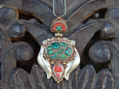 pendaglio tibetano / nepalese in argento con turchesi e corallo  pezzo unico lavorato artigianalmente tutto originale ed autentico .  cesellato ed inciso con i simboli del buon auspicio tibetano .  peso 24 gr  dimensioni 6x4x1 cm